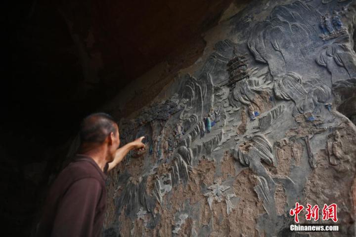 7月15日，甘肅省平?jīng)鍪袥艽h百里石窟長廊羅漢洞石窟內(nèi)，該窟文保員郭建平介紹窟內(nèi)石刻彩繪壁畫。郭建平家中三代人曾自發(fā)保護羅漢洞石窟。羅漢洞石窟遺存40余個窟龕，以北魏至清代風(fēng)格為主。中新社記者 李亞龍 攝